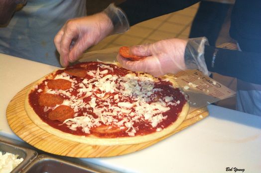 Pizza assembly by skilled hands.