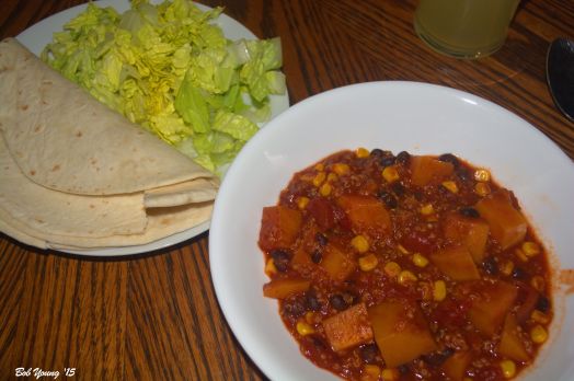 The chili is plated with tortillas and shredded lettuce.