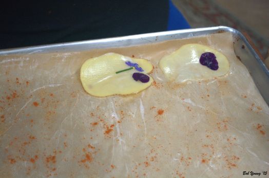 Slice a potato thin enough to be transparent. Lay on the buttered parchment and place the herbs and flowers. Butter the herbs/flowers.