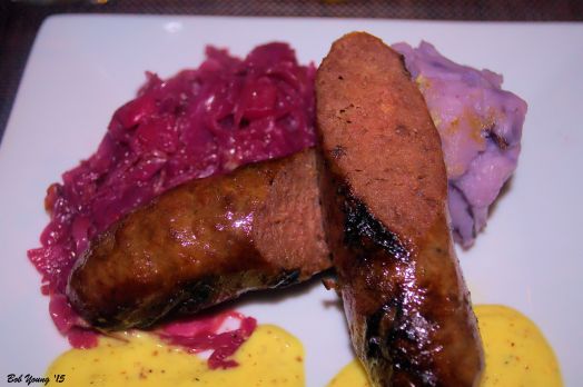 Bison Bratwurst with braised red cabbage, all blue potato puree, mustard cream sauce, garlic hips