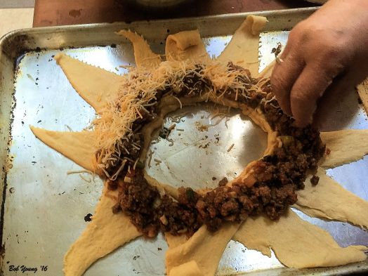 Crescent rolls are unpacked and laid in a circle on a sheet pan. Fry off about 1 lbs of hamburger mixed with some garlic and green onion. Add some Mexican spices and some salsa.