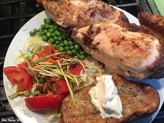 The plated dinner. Grilled Potato with Sour Cream Green Salad with Tomato, Green Onion and Corn Shoots Green Peas Spatchcock Grilled Chicken