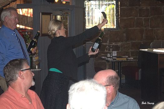 Logan Symser, General Manager, sabers a bottle of champagne.